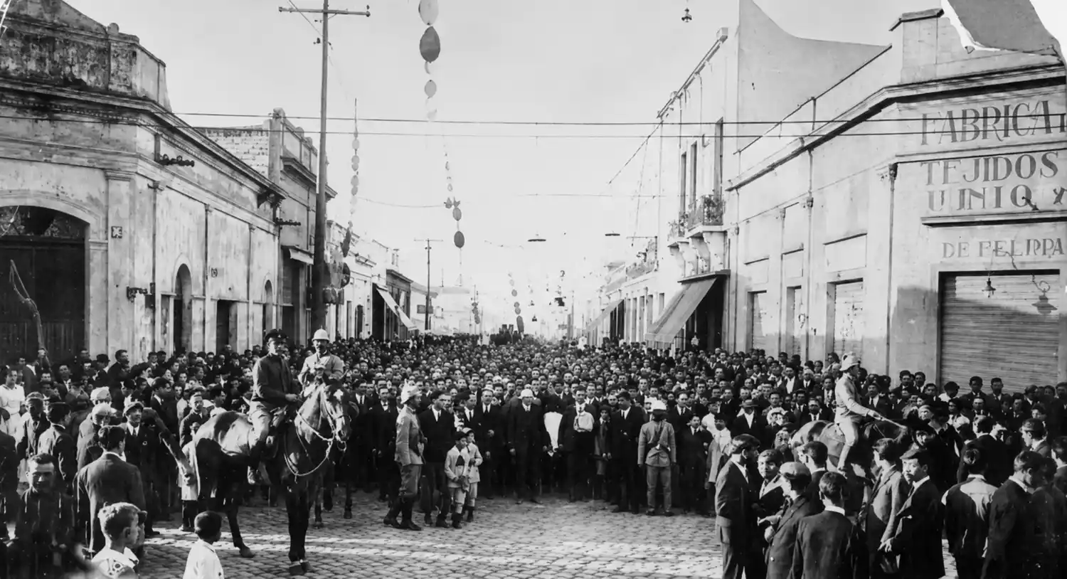 Esta foto, tomada el lunes 5 de mayo de 1930 en la intersección de la calle Pinto y avenida Santamarina, señala la ruta del cementerio de los policías alevosamente asesinados el día anterior en la cancha de las Ferias Francas. El vecindario conmovido, acompaña los restos de los servidores públicos. Al frente, a la izquierda, casco blanco, se distingue sobre su cabalgadura el sargento José Francisco Espinosa, encargado del Destacamento de Iraola, quien años después habría de resultar herido de un balazo cuando intento detener al asesino "Pólvora".