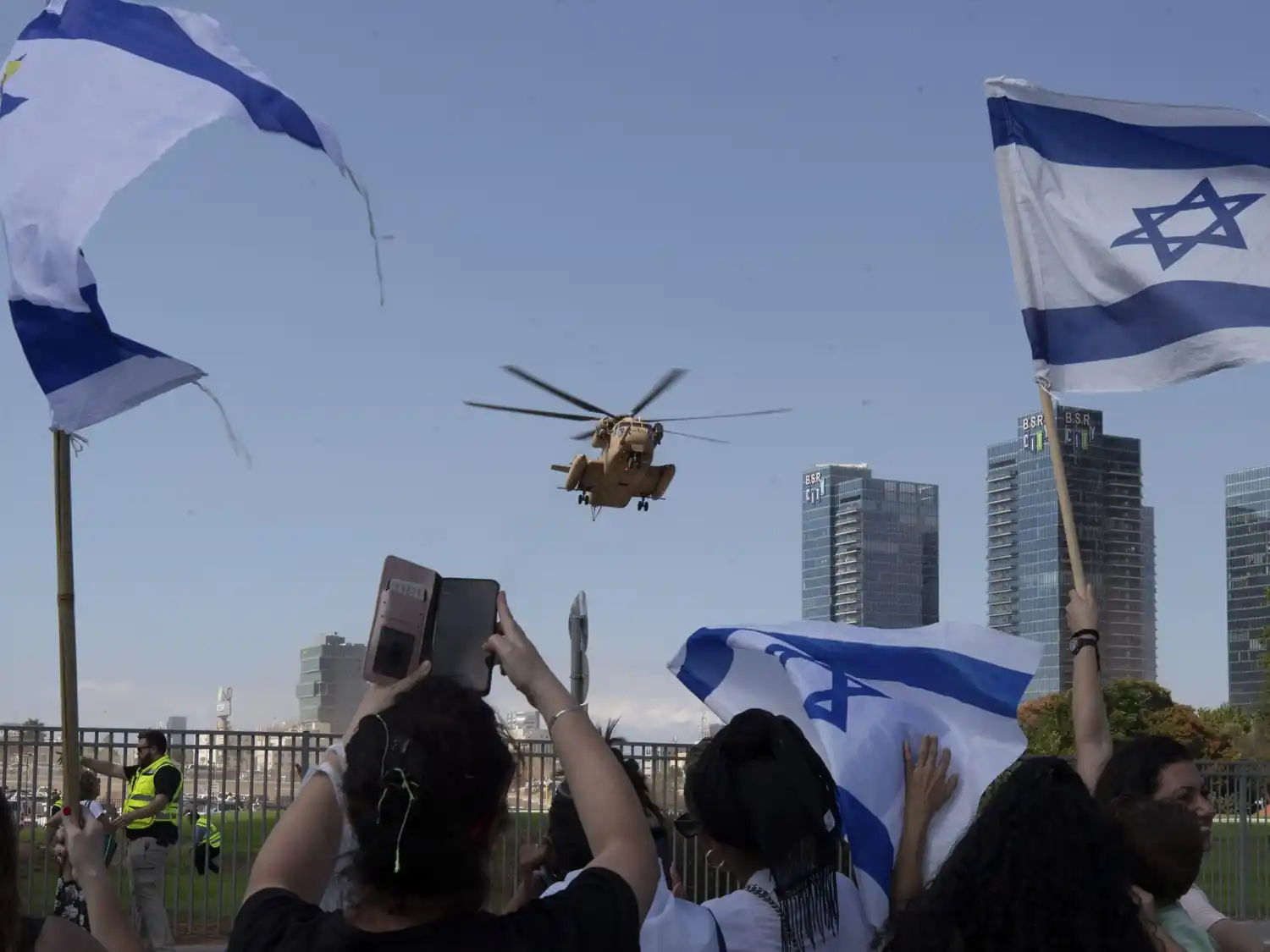 Personas festejan mientras el helicóptero que transporta a los rehenes liberados llega a un hospital, en Petah Tikva, Israel.