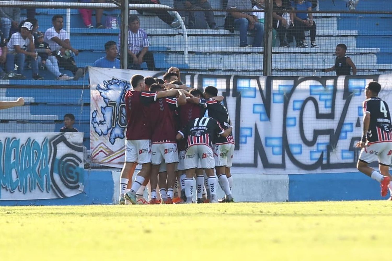 Titulares y suplentes abrazan a Pombo luego del gol (Prensa Chacarita).