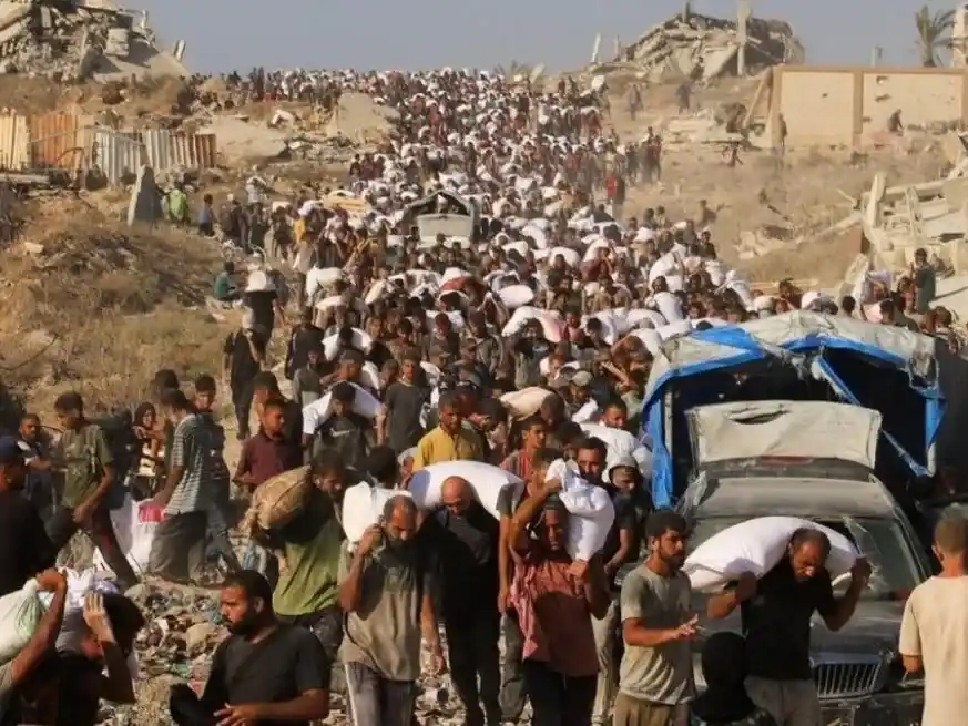 Palestinos cargan a pie con alimentos y otros bienes de ayuda humanitaria en Beit Lahia, Franja de Gaza.