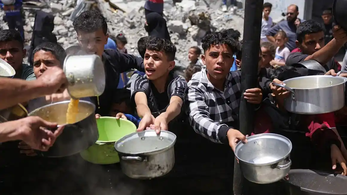 Palestinos desplazados se reúnen para recolectar porciones de comida en una distribución benéfica en Jabalia, al norte de Gaza, el 19 de mayo de 2025. BASHAR TALEB/AFP/AFP via Getty Images