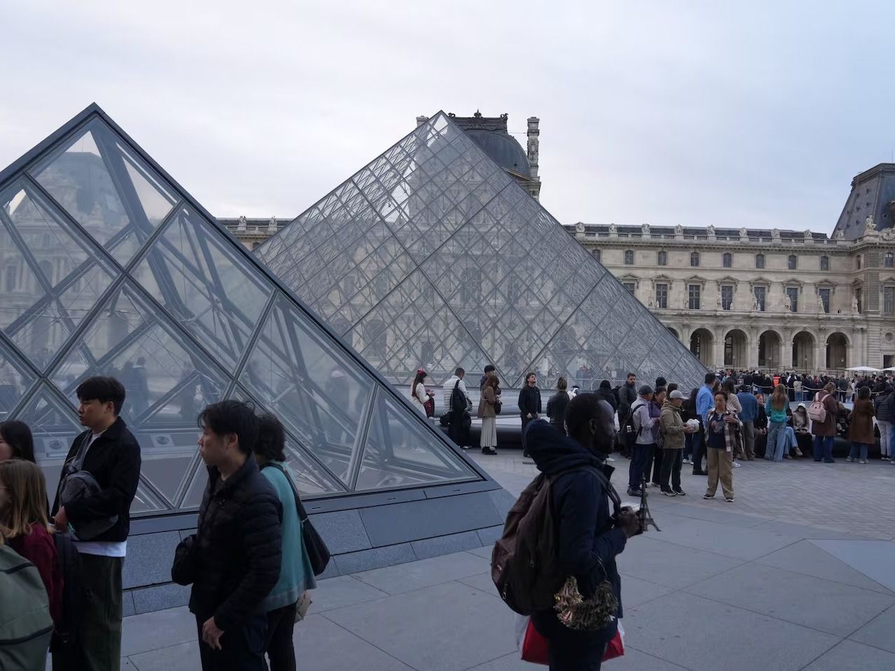 Visitantes hacen fila para entrar en el museo del Louvre tres días después del robo de joyas históricas a plena luz del día, el 22 de octubre de 2025 en París. (AP Foto/Thibault Camus)