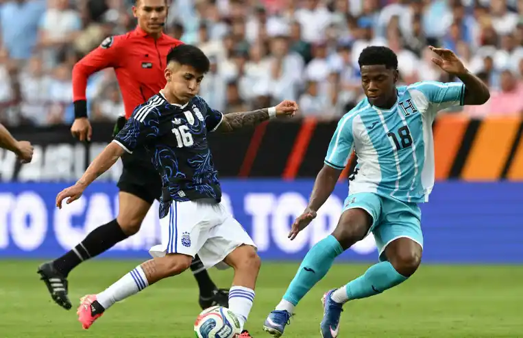 Thiago Almada lanza un pase ante la marca de Dereck Moncada (Créditos: RONALDO SCHEMIDT / AFP)