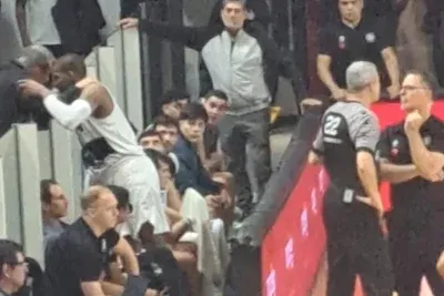 Maxwell hablando con un dirigente en la tribuna mientras lo mira Capelli