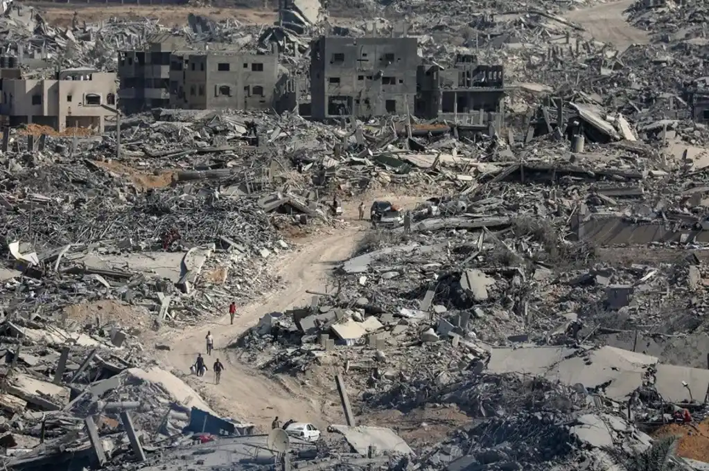 Palestinos desplazados caminando a través de edificios destruidos, en Ciudad de Gaza. EFE