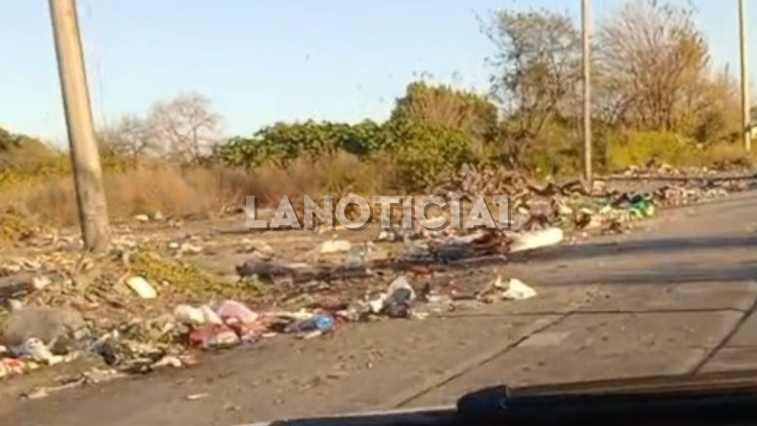 Un basural a cielo abierto frente a una plaza donde juegan chicos.