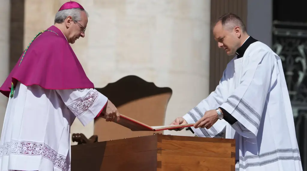 Dos oficiantes del funeral del papa Francisco colocan el Evangelio abierto sobre su féretro.