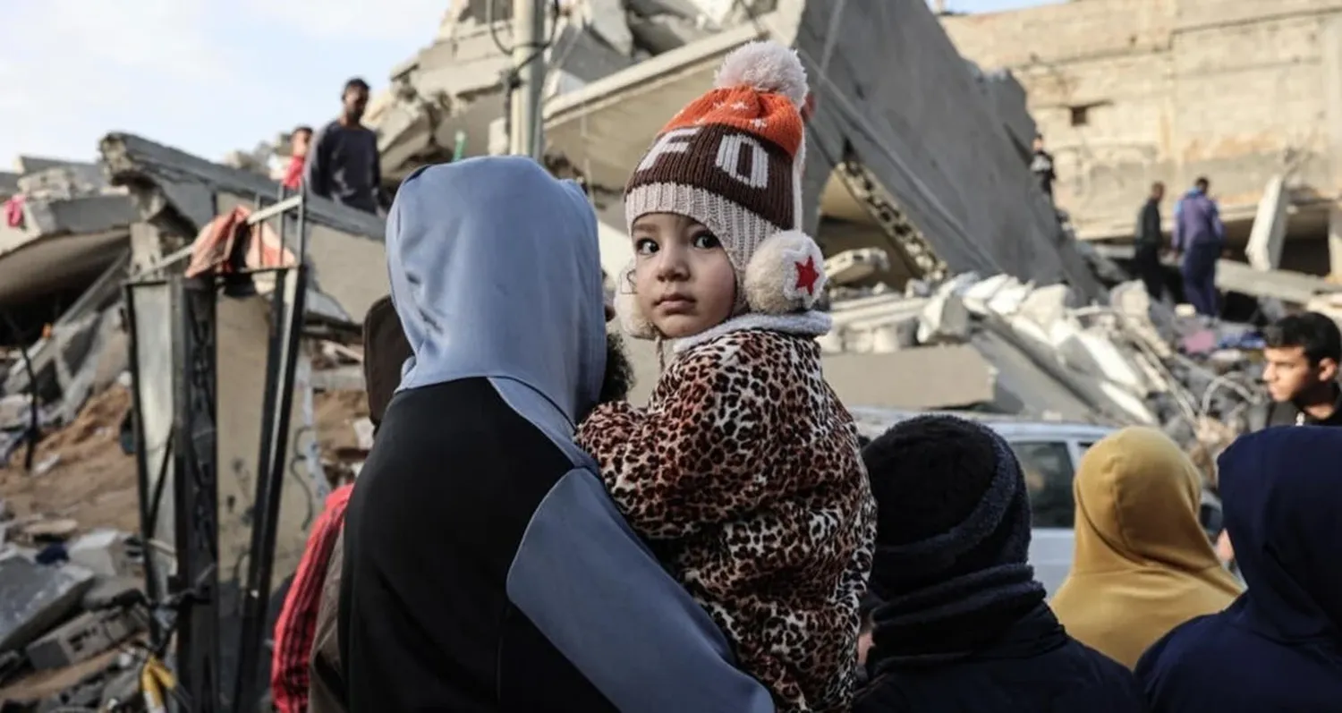 Palestinos delante de los escombros de un edificio bombardeado por fuerzas israelíes en Rafah, al sur de Gaza.