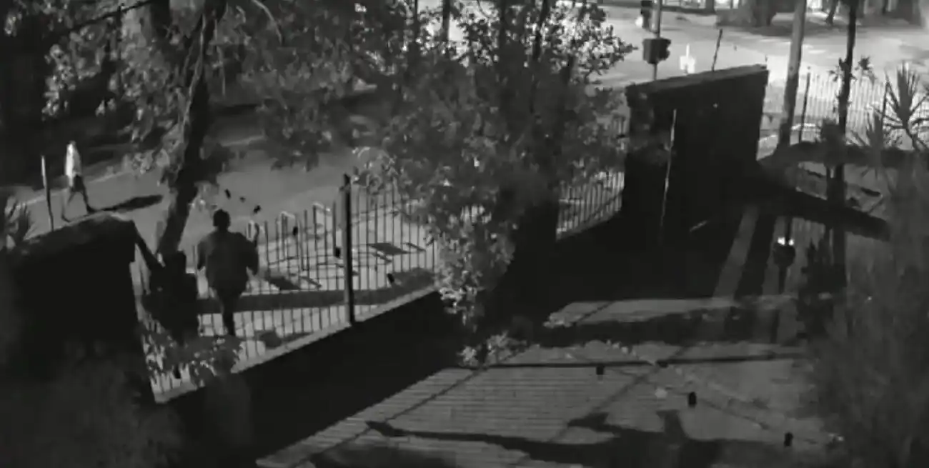 El momento en que tres delincuentes fugan del comercio trepando por la reja.