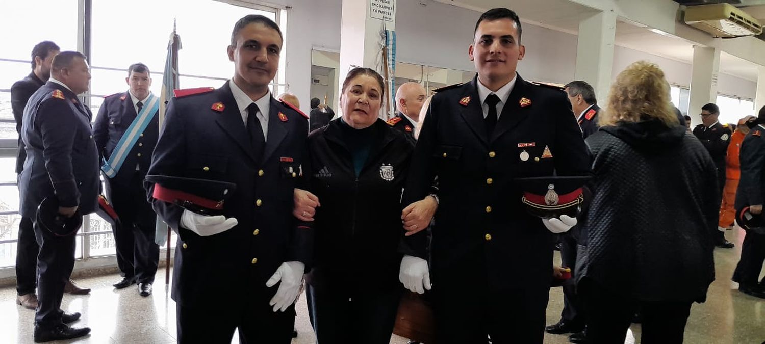 Clara tomando del brazo a dos bomberos, en ellos representa el abrazo para todos los integrantes del cuerpo activo