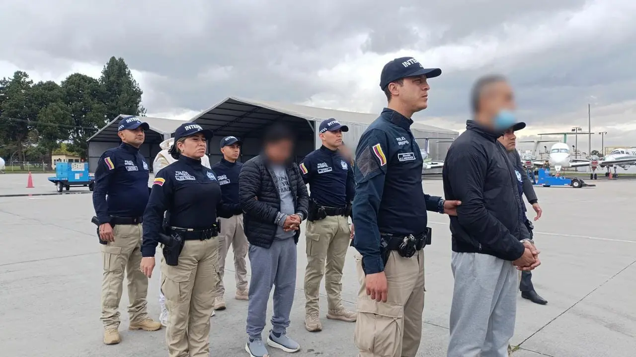 Agentes de la Policía Nacional y de Interpol escoltan a cuatro ciudadanos colombianos requeridos por las autoridades de Estados Unidos por delitos relacionados con narcotráfico, antes de ser extraditados desde el aeropuerto de Bogotá.