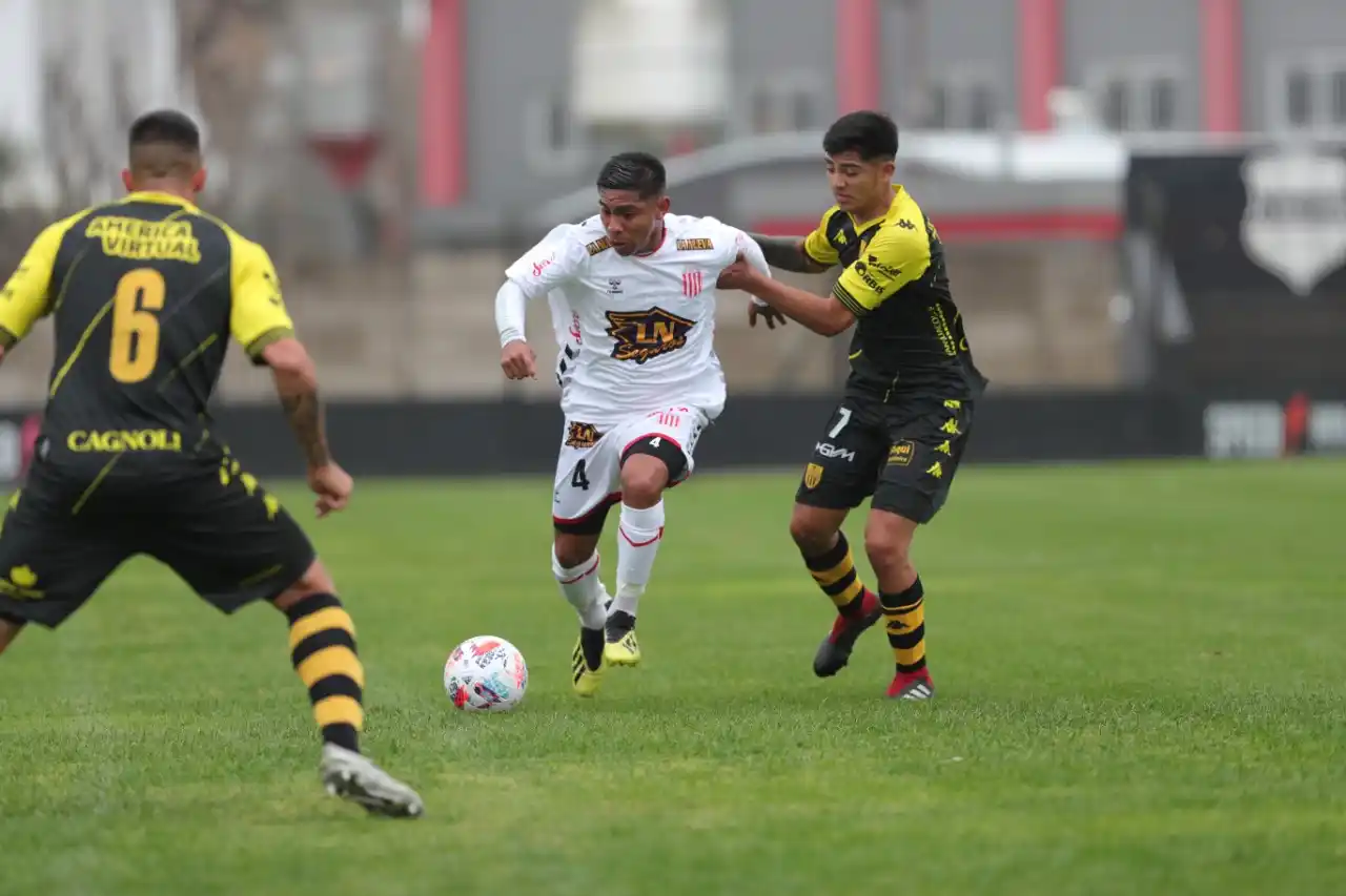 FOTOS PRENSA BARRACAS CENTRAL Rivero es seguido de cerca por Santillán, con Jara esperando de frente a la jugada.