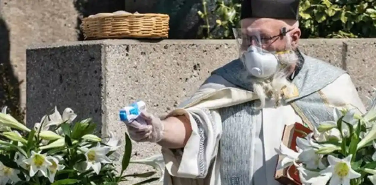 Un sacerdote utiliza una pistola de agua para realizar las bendiciones