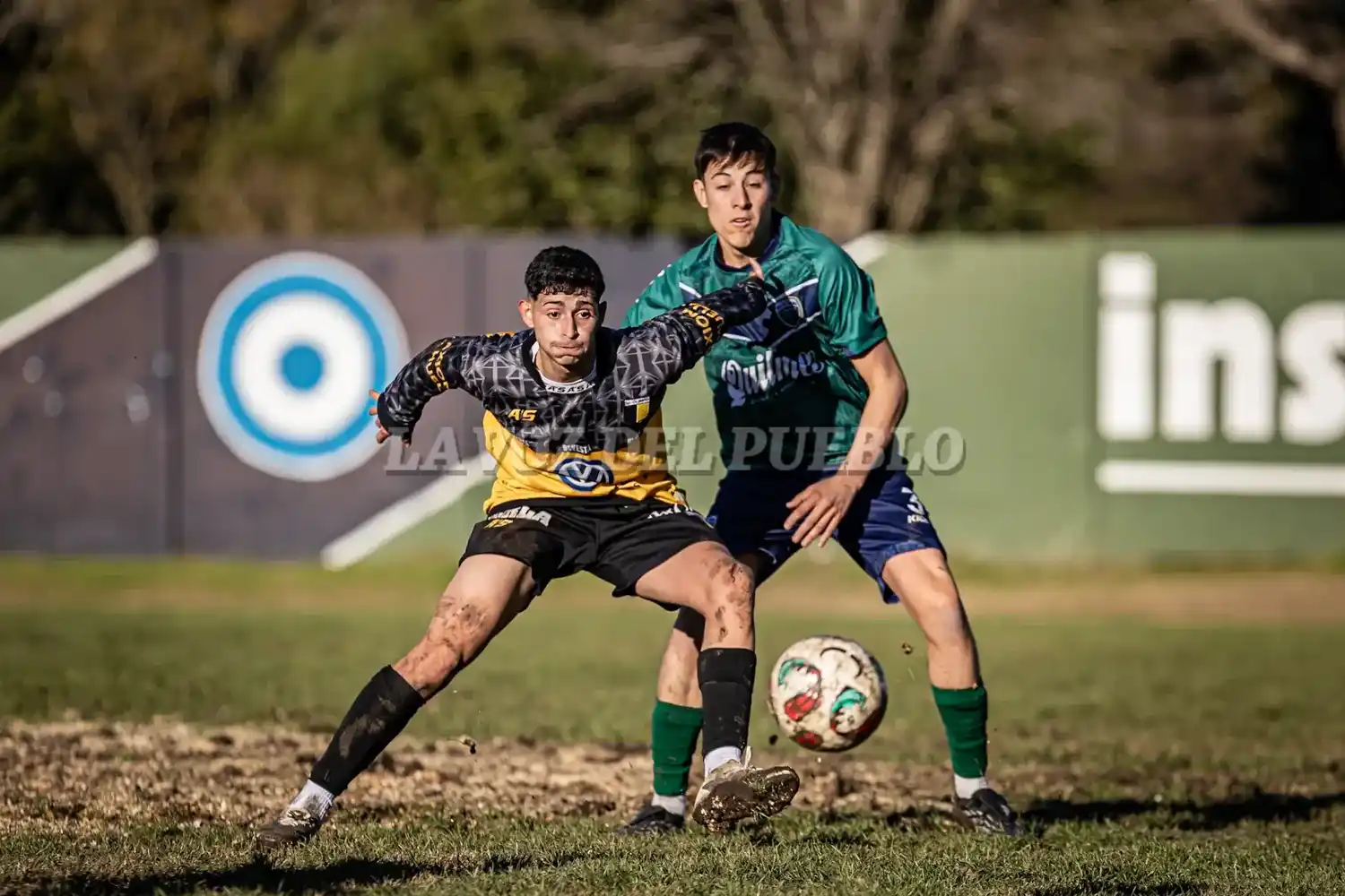 Julián Allema de Olimpo aguarda por recibir la pelota ante la presión de Agustín Irastorza de Villa