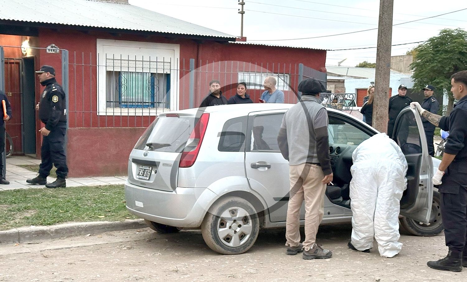 Peritos revisan el auto de la mujer, frente a la casa donde ocurrió el hecho