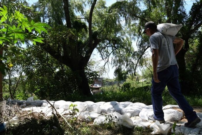 En La Vuelta del Paraguayo, hay familias que huyen de la crecida. Otras resisten haciendo contenciones con bolsas de arena. Mauricio Garín