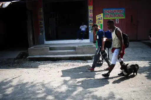 El migrante venezolano Gilberto Rodríguez (R) camina con su perro llamado Negro (Black) y su compañero migrante Darwin Montiel en una calle de Tecun Uman, Guatemala, en la frontera con Ciudad Hidalgo, México