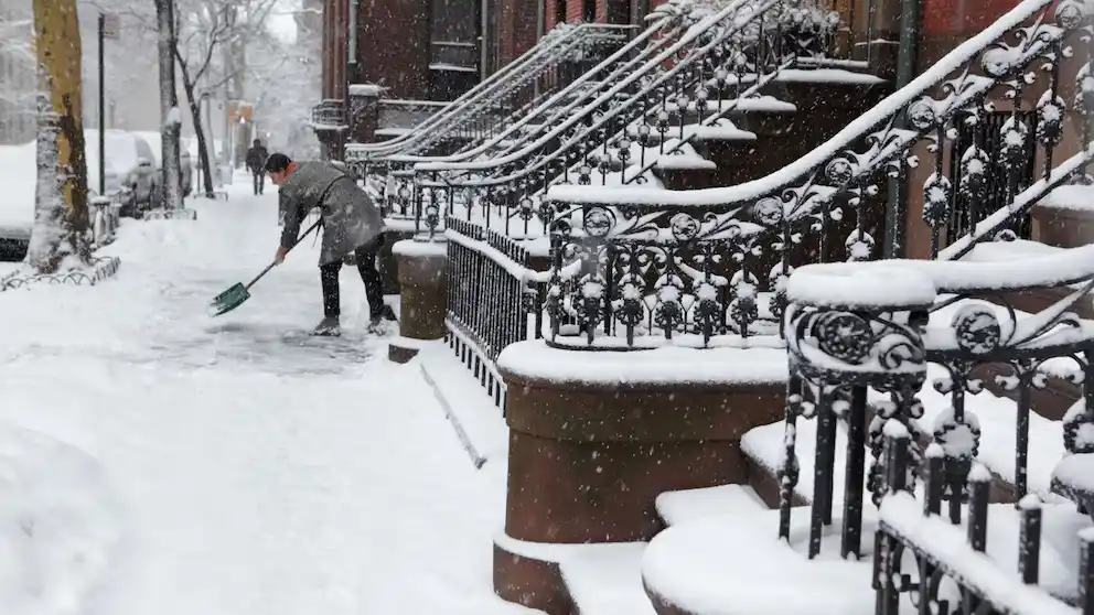 residente despeja la vereda frente a su vivienda en un barrio de Nueva York, luego de las precipitaciones registradas durante el fin de semana.