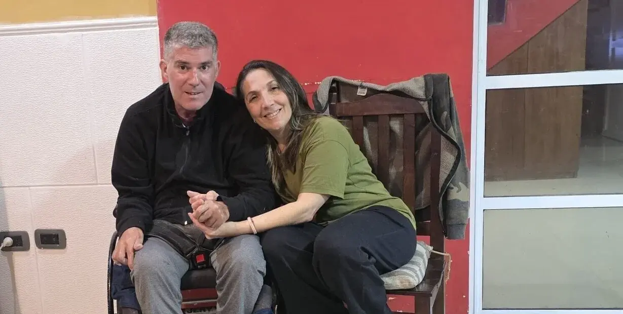 César Fernández (54) quedó con secuelas motrices y neurológicas tras un infarto sufrido en su trabajo en 2021. Al lado, su pilar y sostén, Alejandra Mir. Foto: Clarín
