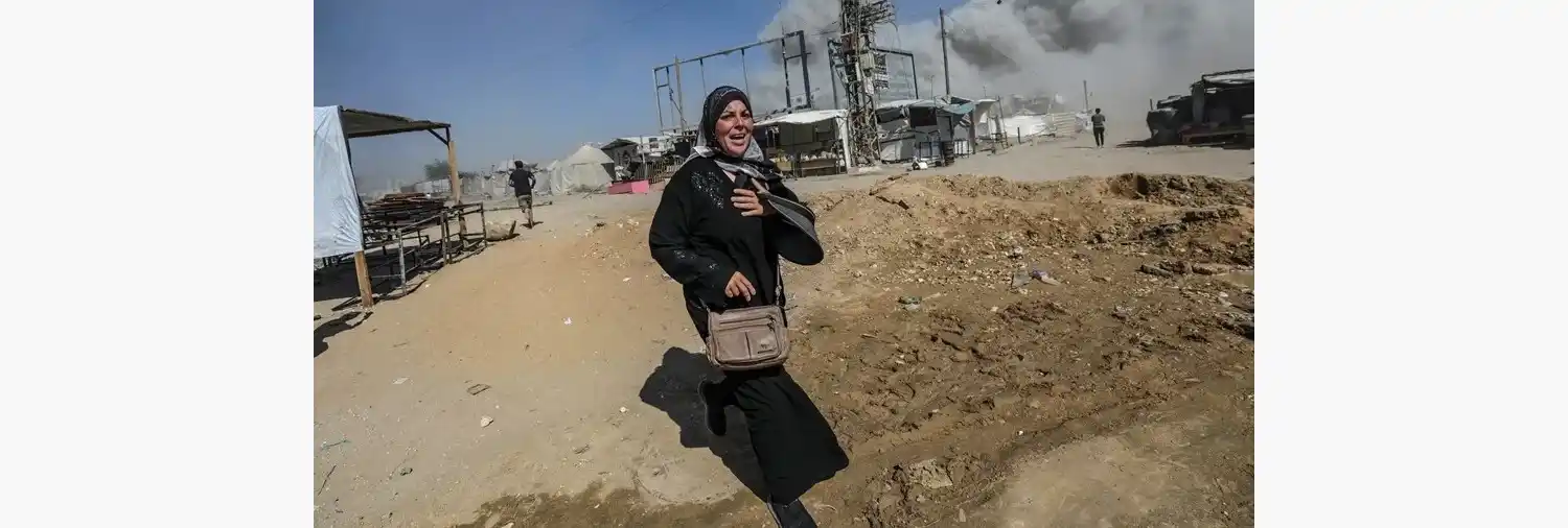 Una mujer palestina corre a refugiarse tras un ataque aéreo israelí este lunes en el oeste de la Ciudad de Gaza. EFE/ Mohammed Saber