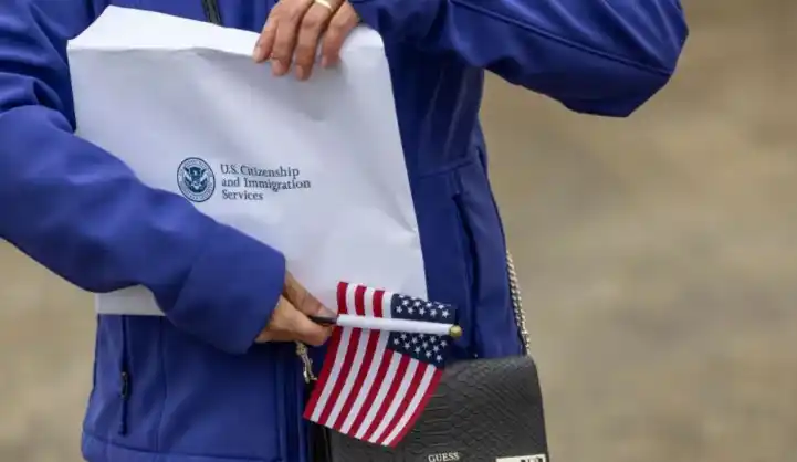 Una nueva ciudadana de EE.UU. sostiene un sobre con su certificado de ciudadanía estadounidense, luego de una ceremonia de naturalización.