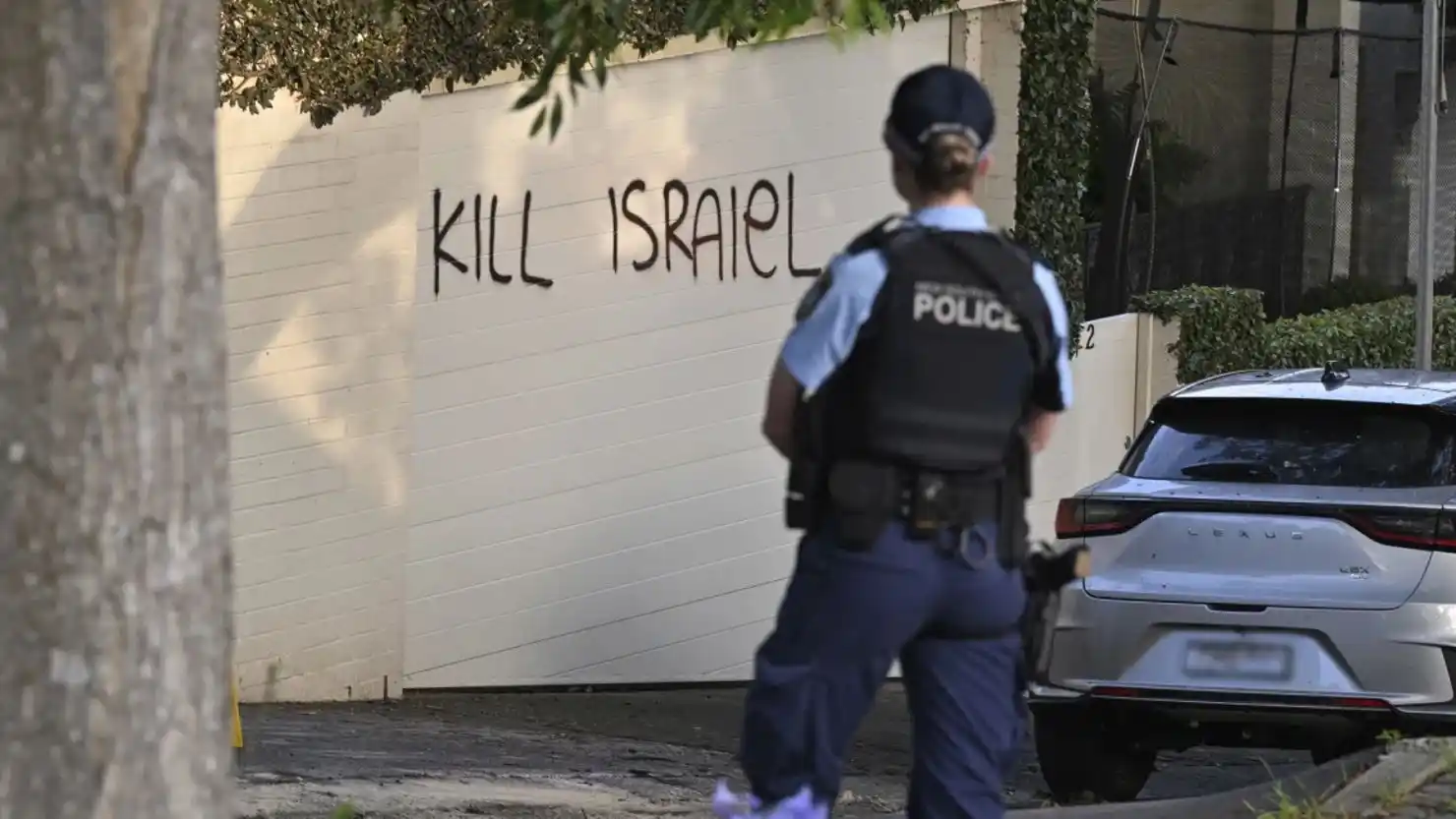 Una agente de Policía se encuentra junto a un grafiti antiisraelí pintado en una pared en Sydney.