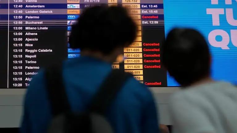 Pasajeros miran las pantallas del aeropuerto Fiumicino de Roma, donde decenas de vuelos fueron cancelados por la falla informática mundial.