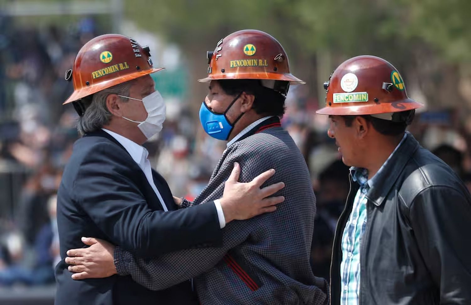 Con los cascos de trabajo de los mineros bolivianos, el expresidente de Bolivia, Evo Morales, en el centro, y el expresidente Alberto Fernández, a la izquierda, se abrazan en medio del puente fronterizo.