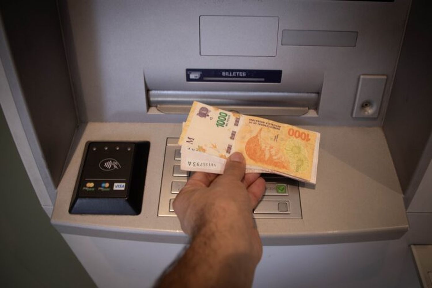 Un hombre retira dinero de una terminal de cajero.