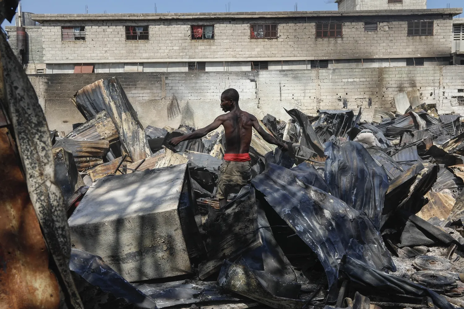 A man looks for salvageable items at a car mechanic shop that was set fire during gang violence in Port-au-Prince, Haiti, on March 25