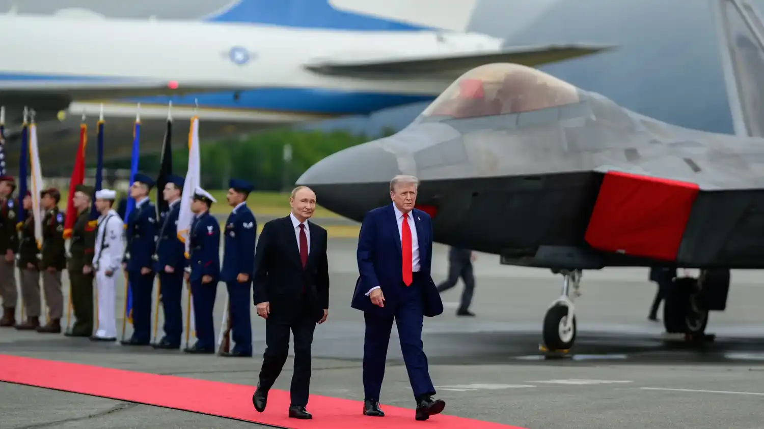 El presidente ruso Vladímir Putin y el mandatario estadounidense Donald Trump caminan juntos por la alfombra roja en Alaska.