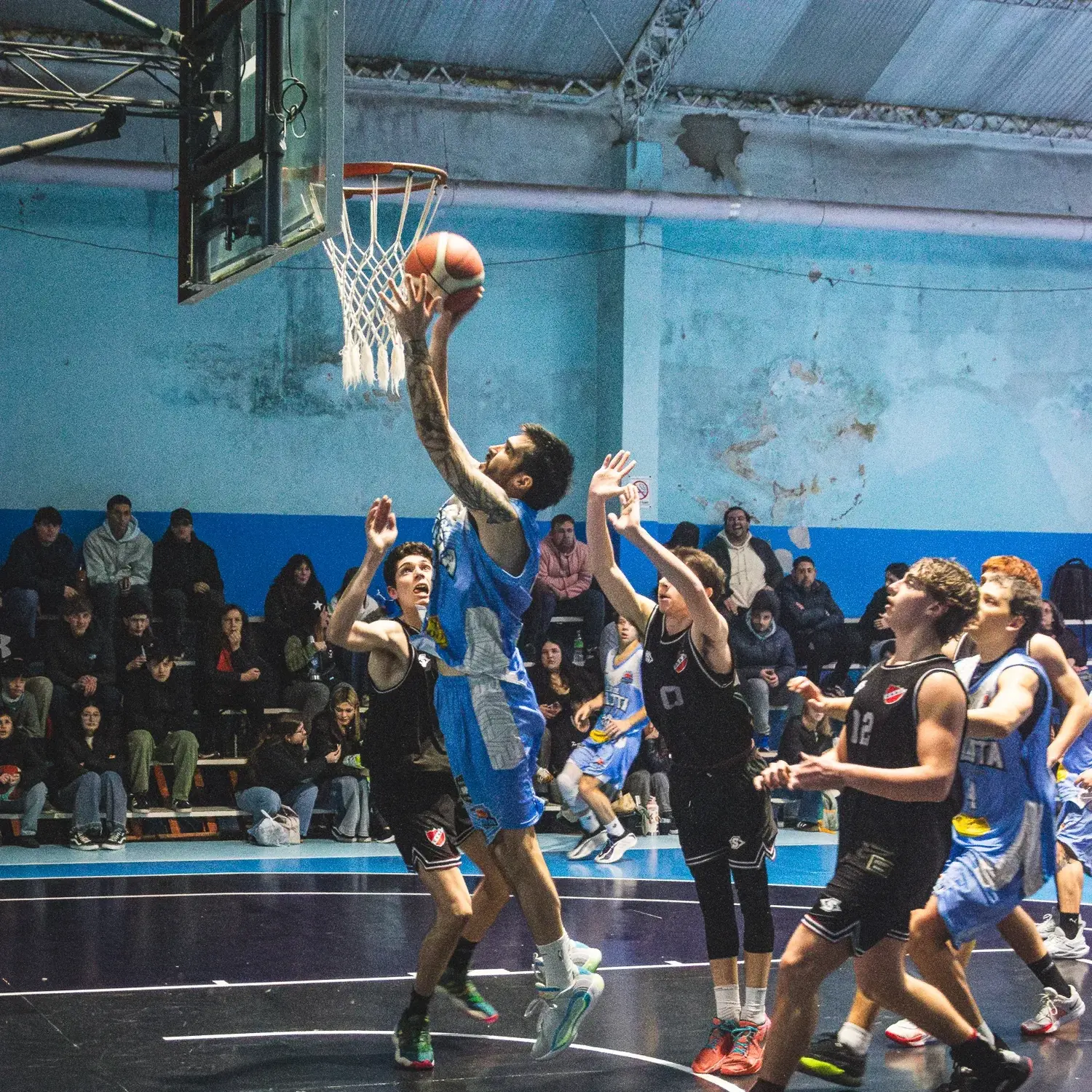 Susemihl ganó la posición y va a anotar abajo del aro ante la observación de Frapiccini, Onzari y Taraborelli