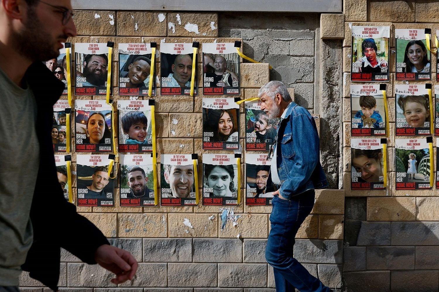 Varias personas caminan junto a pancartas con fotos de los rehenes secuestrados en el ataque del 7 de octubre de Hamás contra Israel.