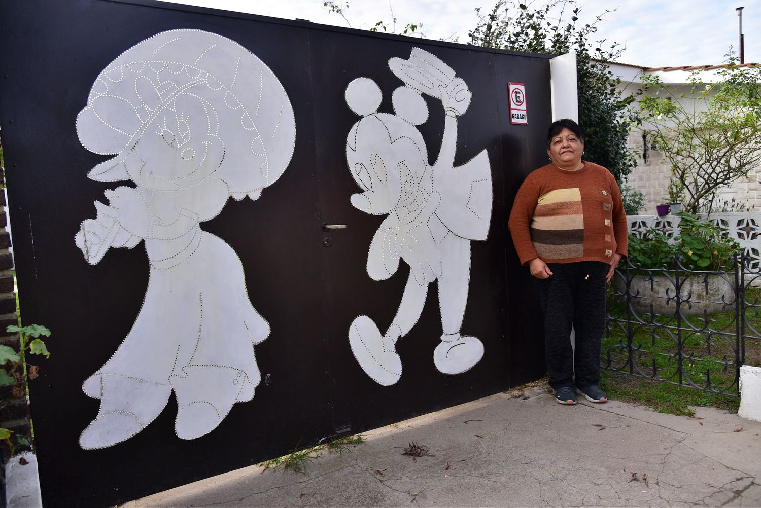 Marcela Ponce frente al portón de su hogar en barrio Cottolengo con las figuras de Minnie y Mickey Mouse.