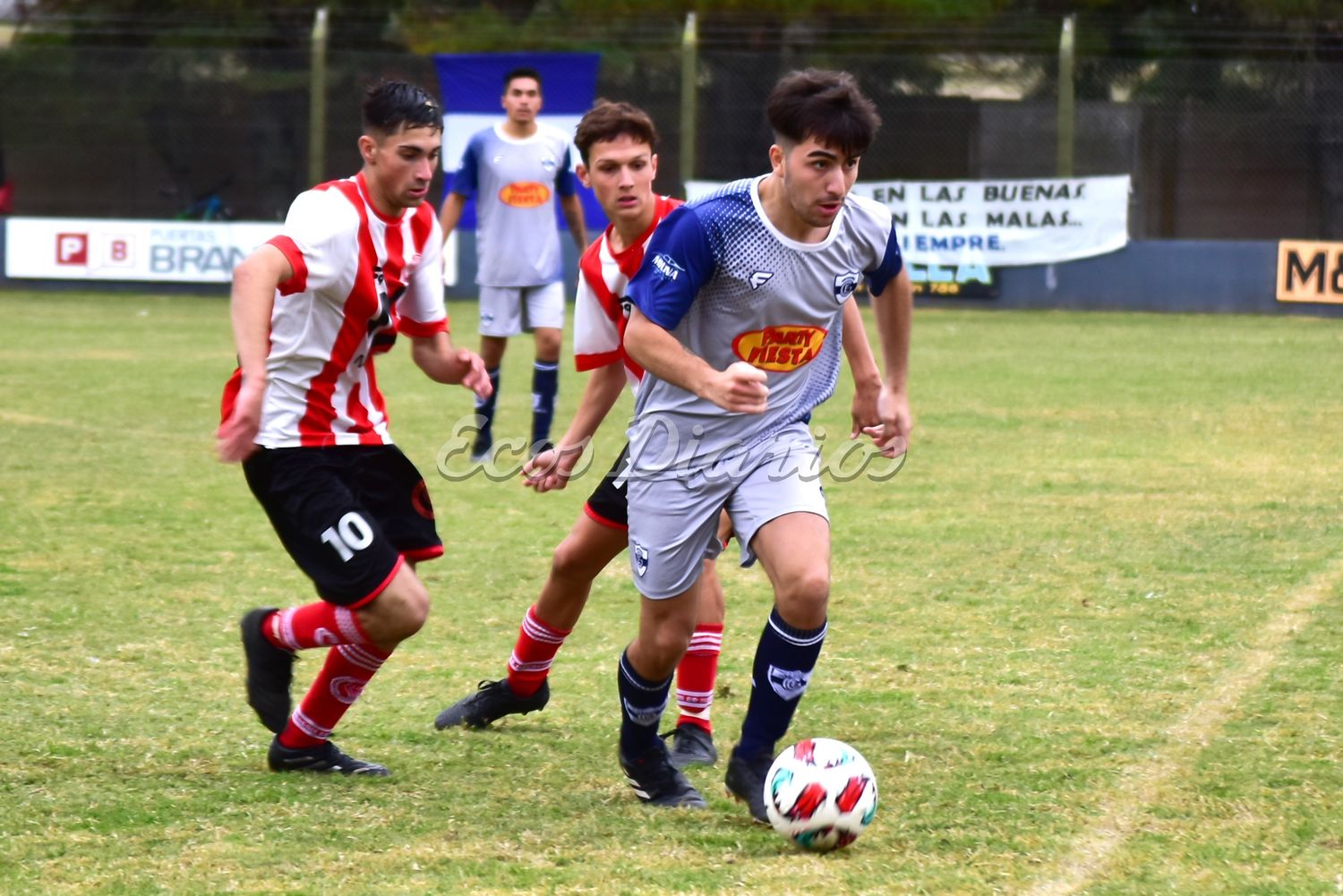 Simón Coronel traslada el balón, ante la marca de dos rivales