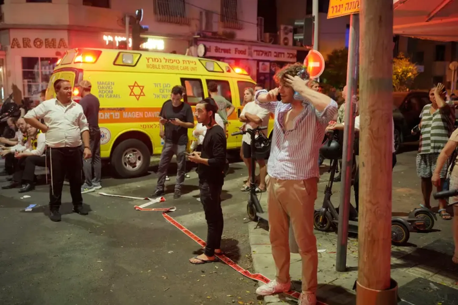 People gather at the scene of a deadly explosion in Tel Aviv, Israel, early on Friday