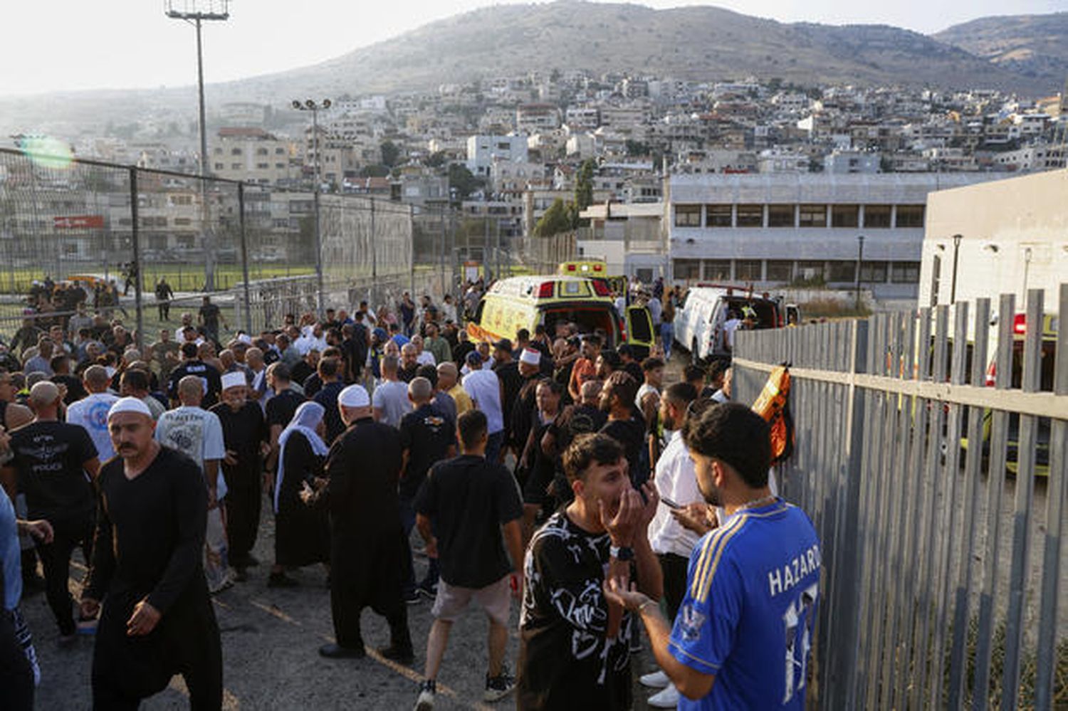 Israeli emergency services and local residents gather near a site where a reported strike from Lebanon fell in Majdal Shams village in the Golan area on July 27, 2024.