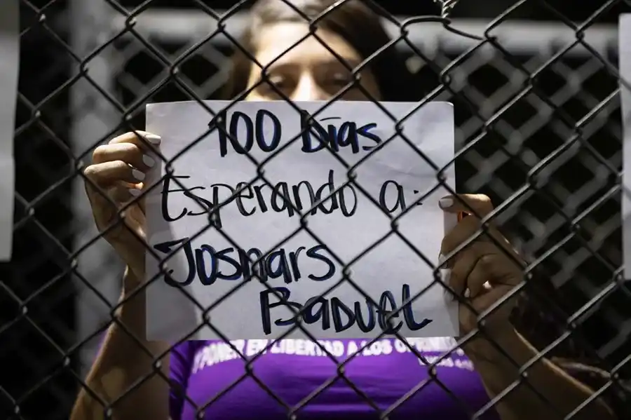 Una persona con un cartel durante una vigilia afuera de la cárcel El Rodeo en Venezuela. EFE