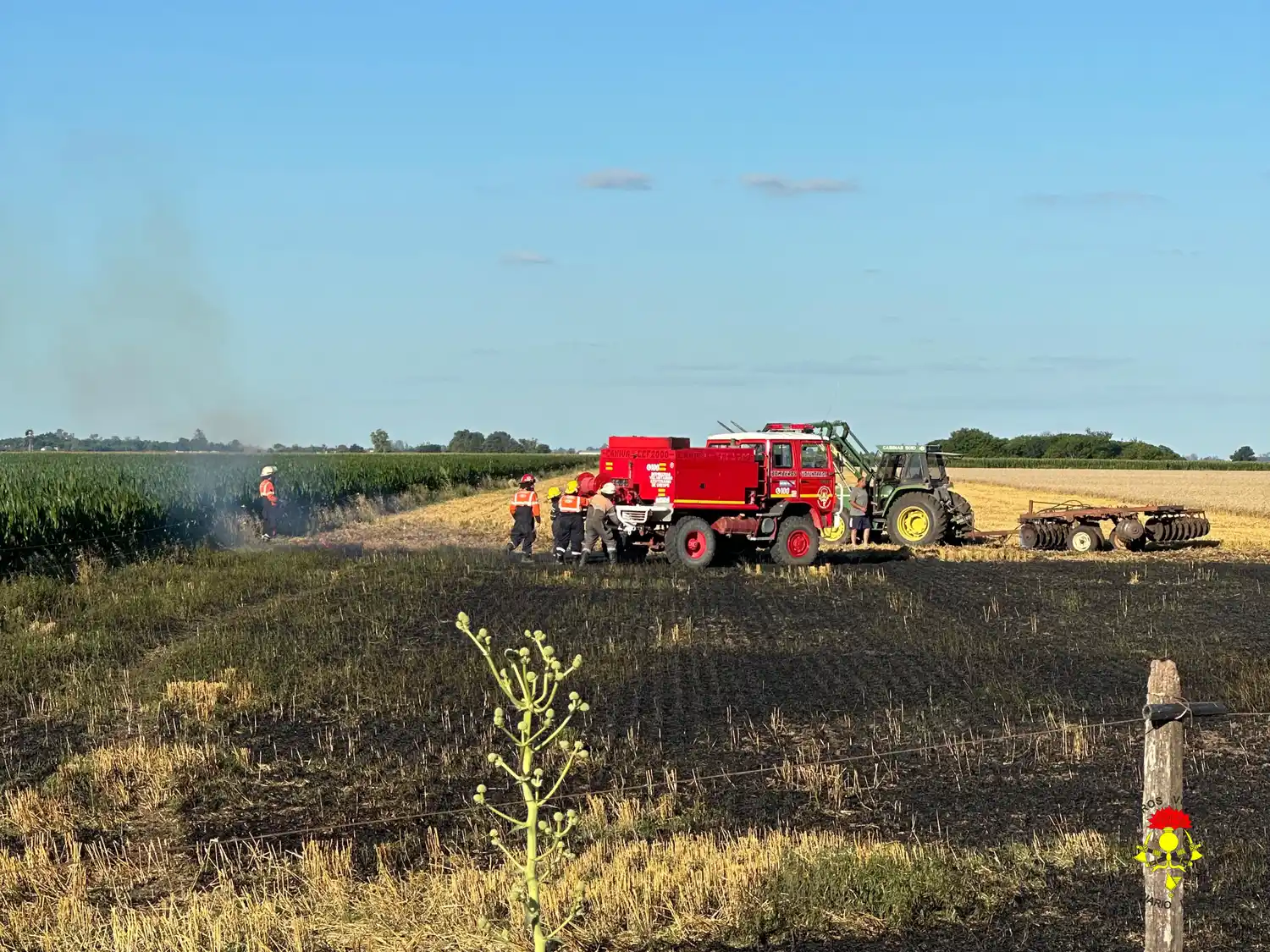 Rápida respuesta de bomberos ante un incendio en un campo con maquinarias agrícolas