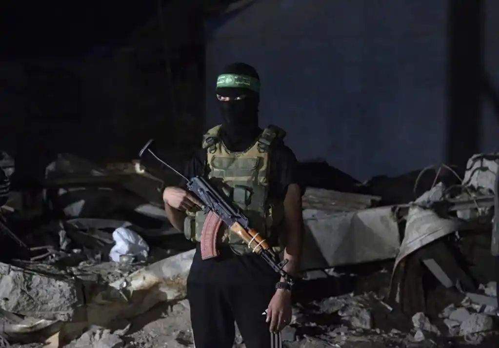 Combatientes palestinos de Hamás vigilan mientras llegan los restos de los rehenes israelíes entregados por Hamás. EFE