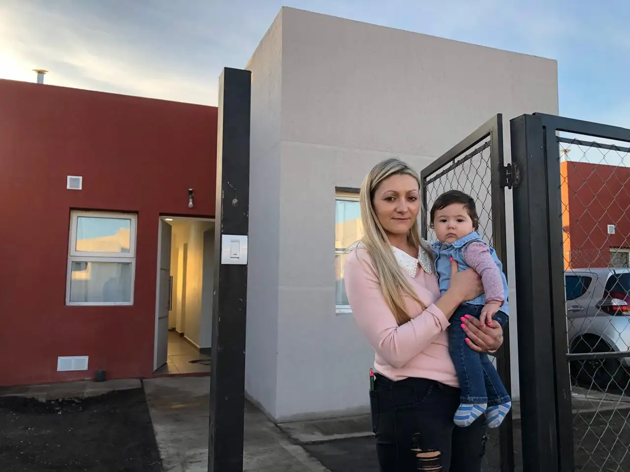 Agustina, su hija más chica, y de fondo su vivienda propia en el Barrio Arco Iris.