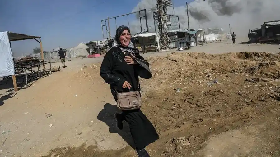 Una mujer palestina corre a refugiarse tras un ataque aéreo israelí este lunes en el oeste de la Ciudad de Gaza. EFE/ Mohammed Saber