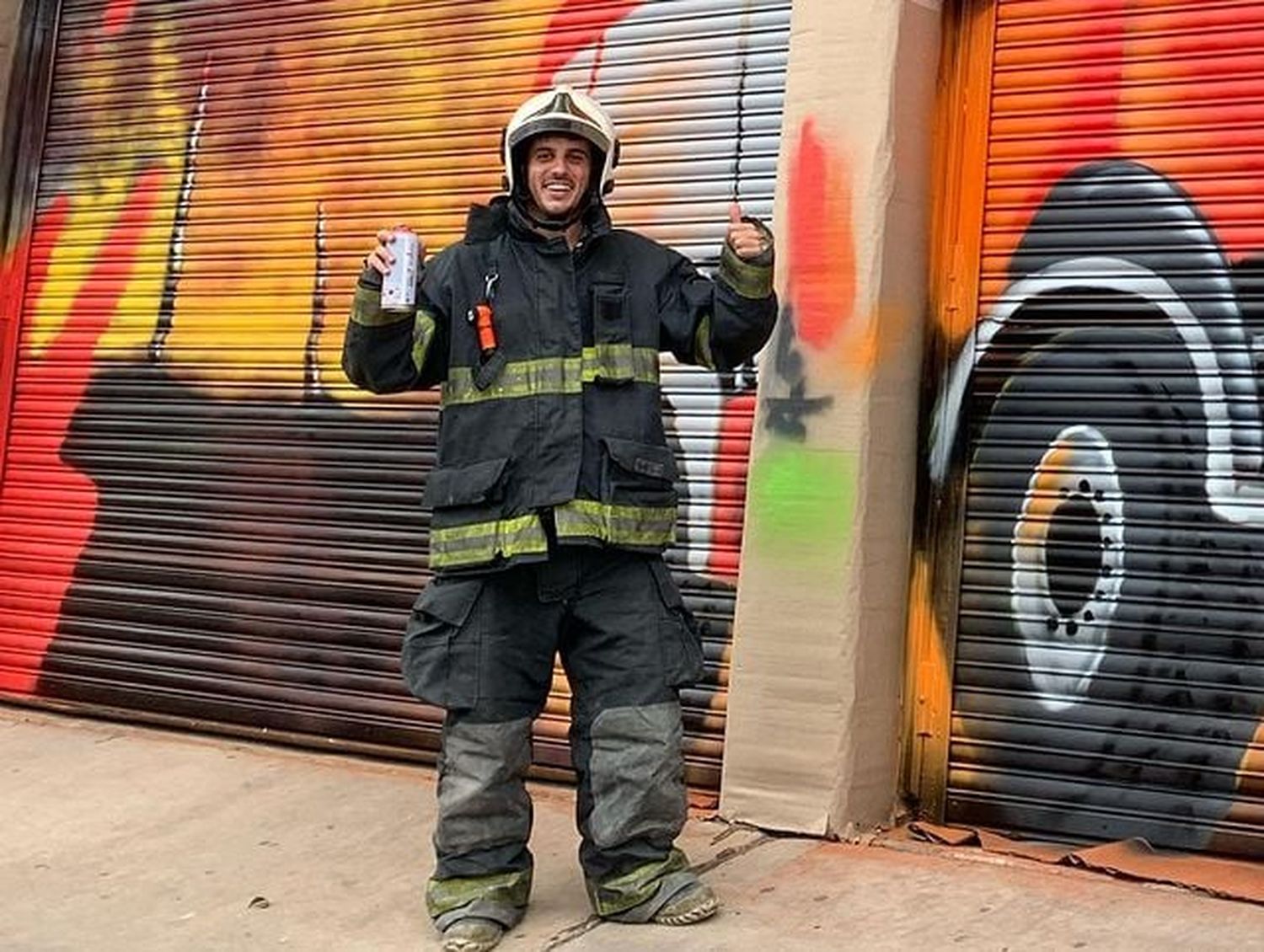 Julián Pastore, artista de San Francisco vestido con un traje de bombero frente a su mural