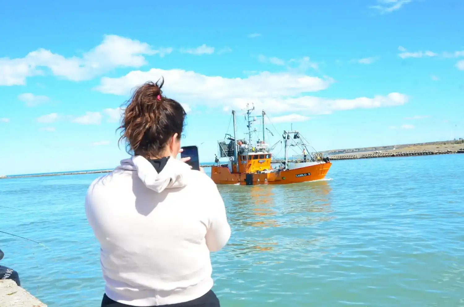 Apasionada por la pesca, Ayelén Lecumbarry le toma fotos a una lancha en el puerto de Rawson