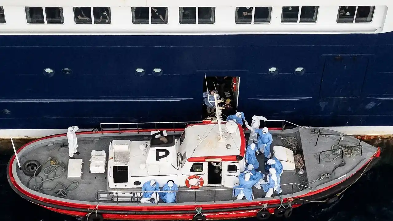 Personal sanitario ayudando a pacientes a subir a un bote desde el crucero MV Hondius, afectado por un brote mortal de hantavirus.