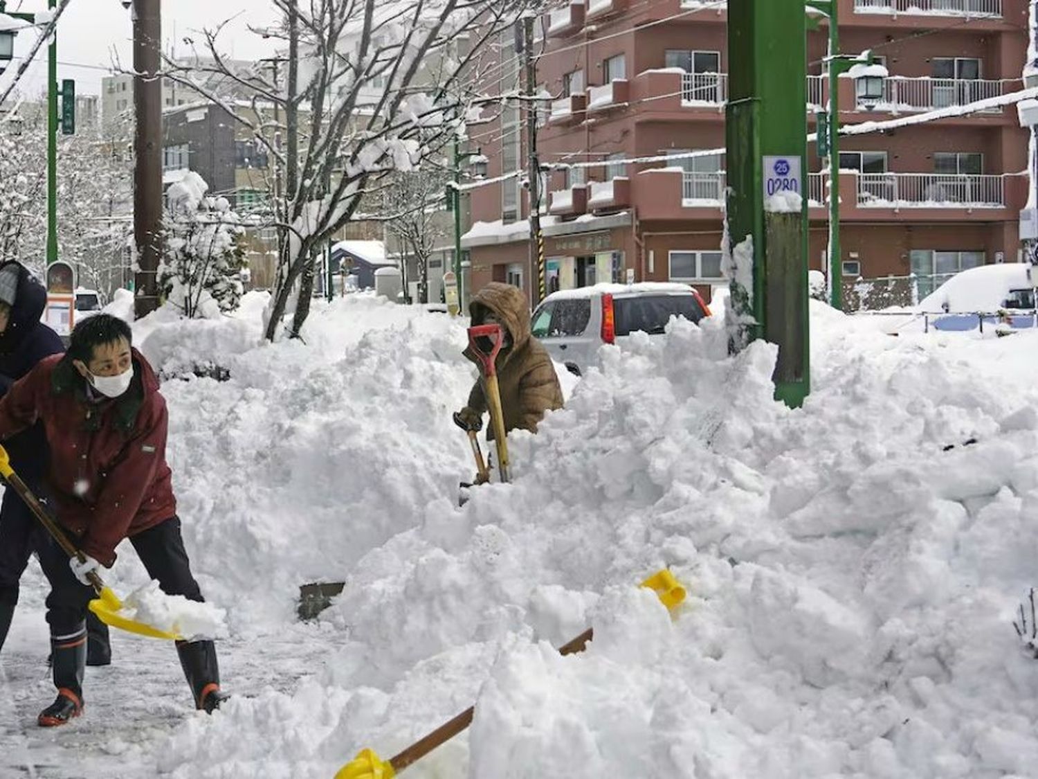 Gente retira nieve de una calle en Kushiro, Hokkaido, Japón. (Kyodo News via AP)