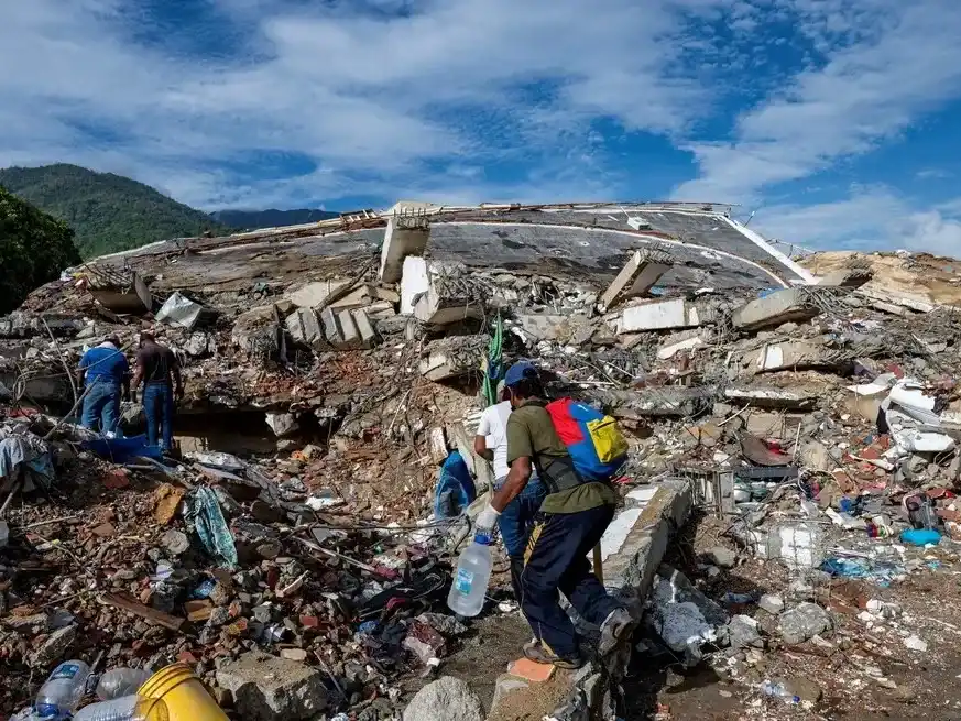 Voluntarios caminan entre los escombros de un edificio derrumbado en Caraballeda.
