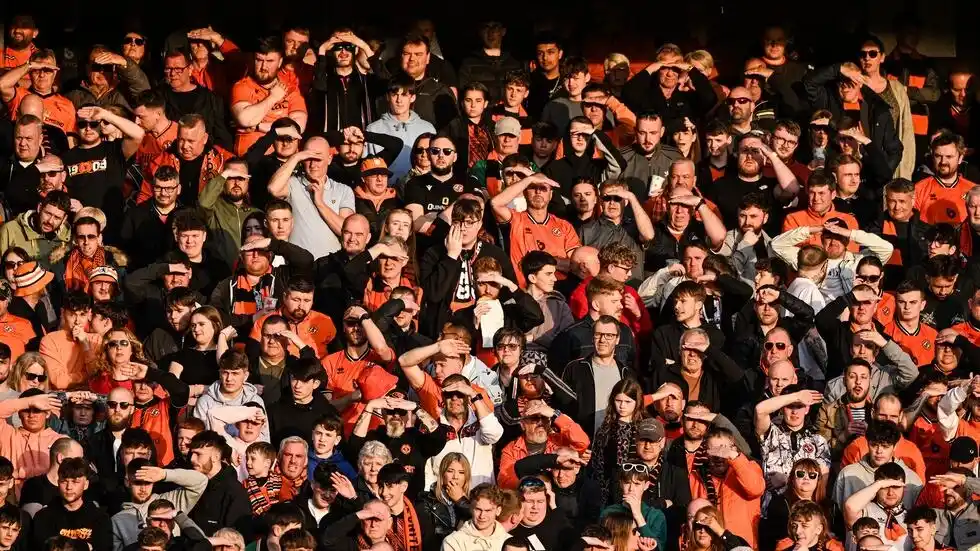 Aficionados del Dundee United se protegen los ojos del sol durante un partido.