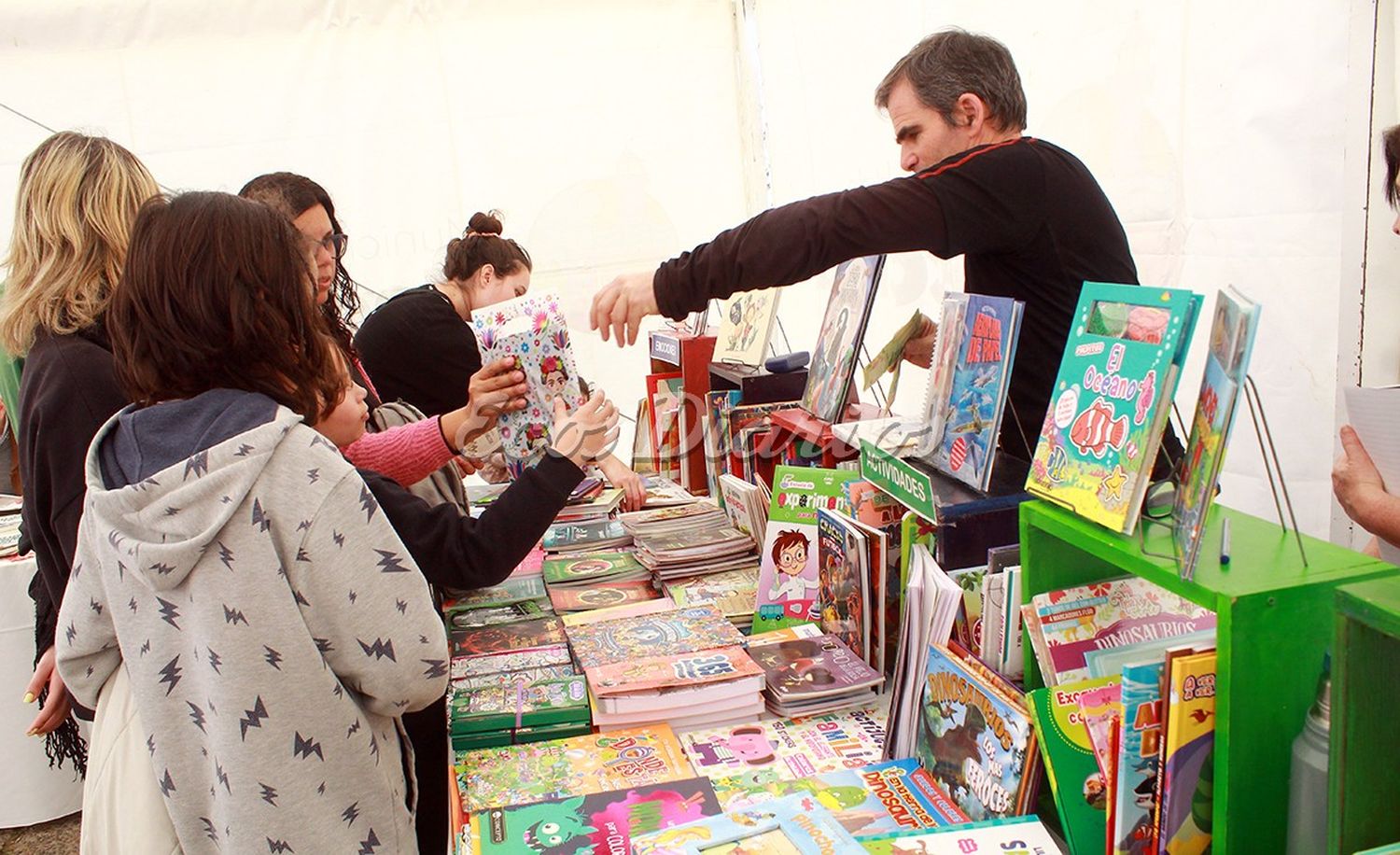 Feria. Un empleado de la editorial entrega un ejemplar de un libro infantil a una niña