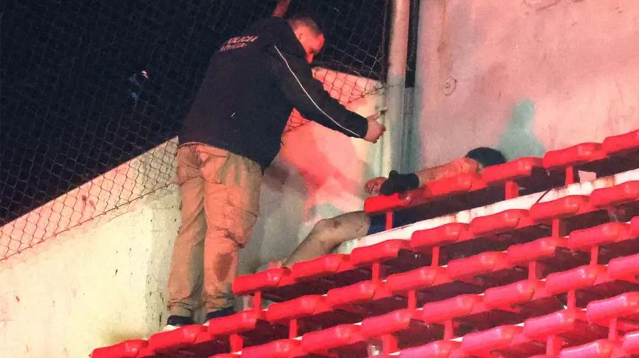 Tarde: un policía bonaerense asiste a un hincha chileno que quedó tendido en la tribuna tras la golpiza.